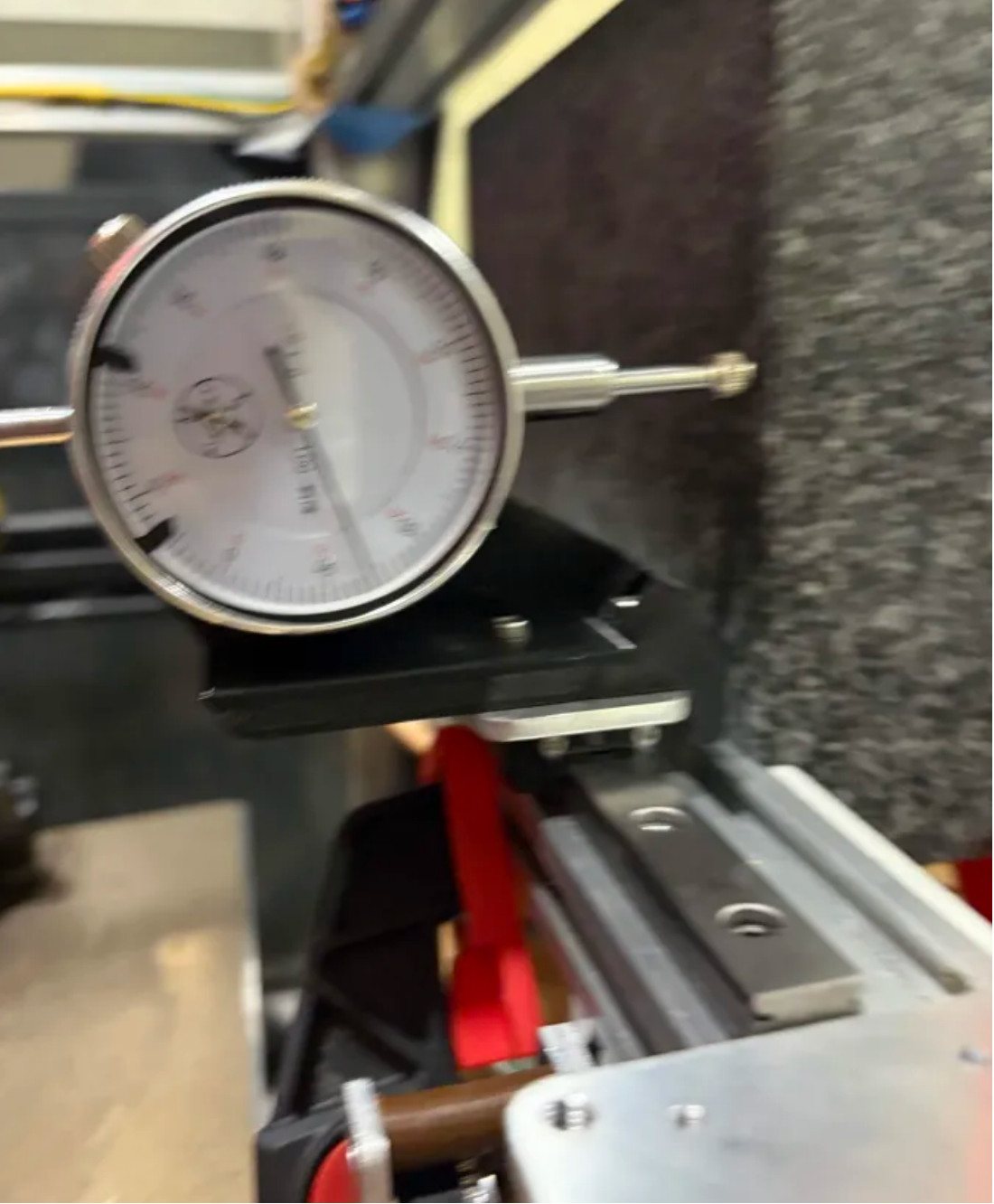 A dial indicator on a linear-rail carriage reading against a granite block