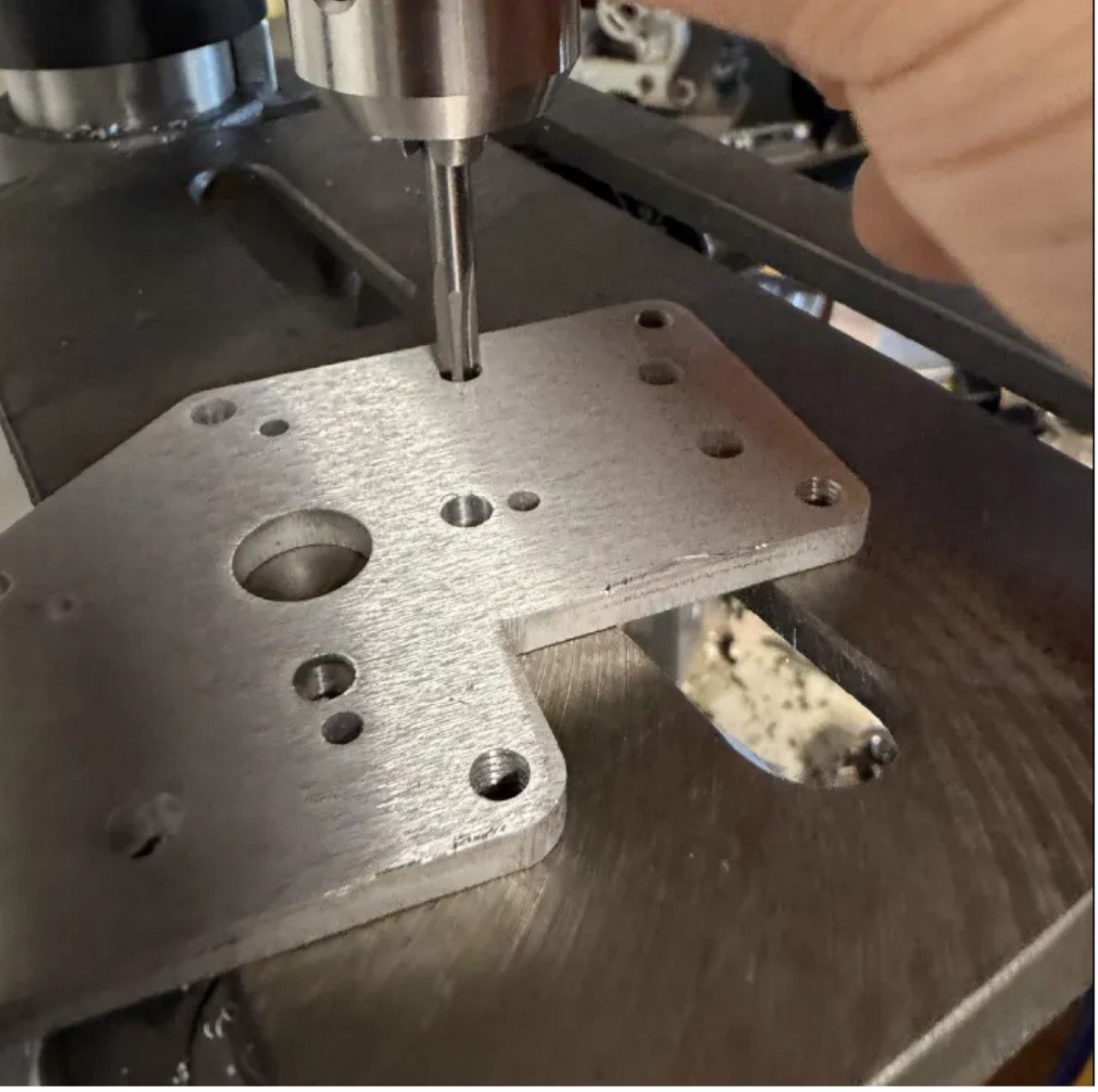A reamer held in a drill press over a sheet-metal plate